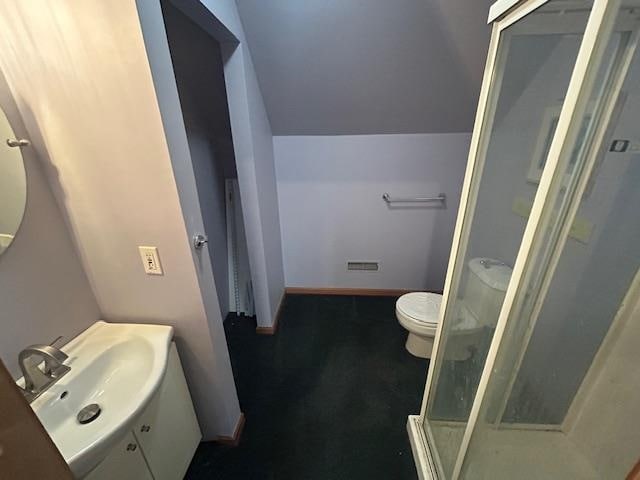 bathroom featuring toilet, vanity, and walk in shower