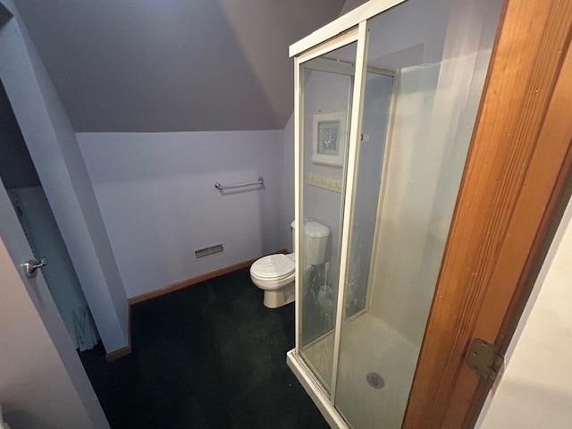 bathroom featuring vaulted ceiling, an enclosed shower, and toilet