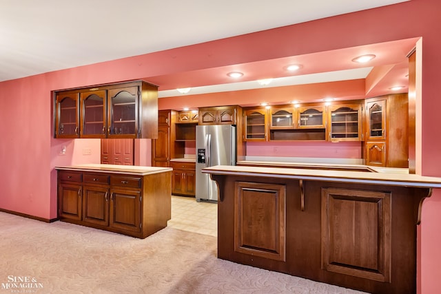 kitchen featuring a kitchen bar, kitchen peninsula, light carpet, and stainless steel refrigerator with ice dispenser