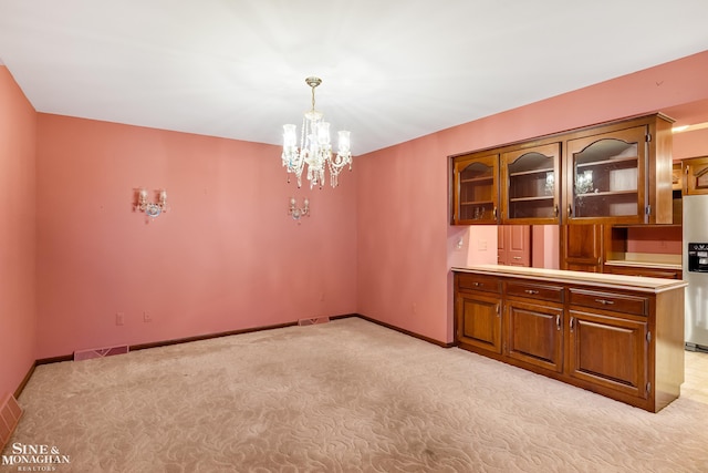 unfurnished dining area featuring a chandelier and light colored carpet