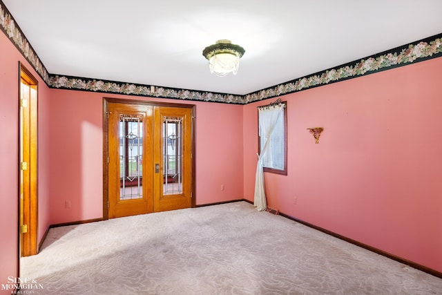 carpeted spare room featuring french doors