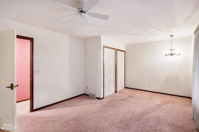 unfurnished bedroom with ceiling fan with notable chandelier and light colored carpet