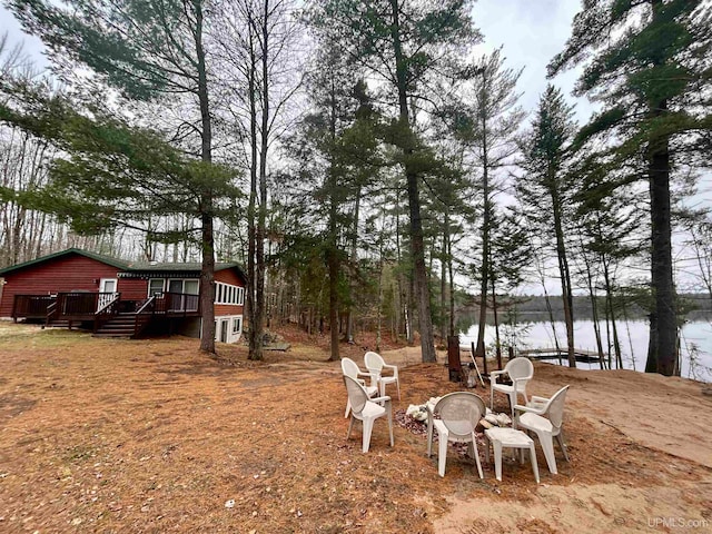 view of yard with a deck with water view and an outdoor fire pit