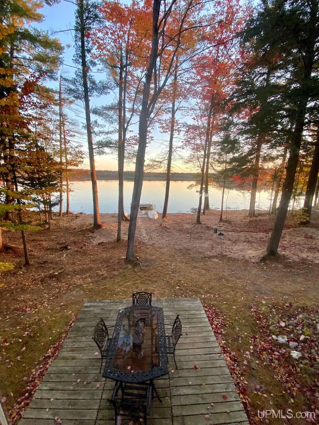 deck at dusk featuring a water view