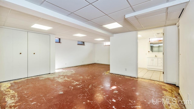 basement with a paneled ceiling and sink