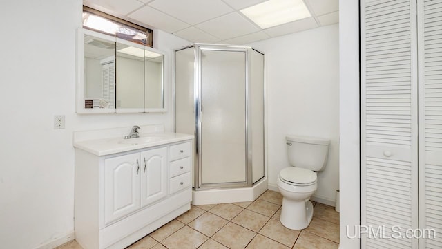 bathroom with toilet, vanity, tile patterned floors, and a drop ceiling