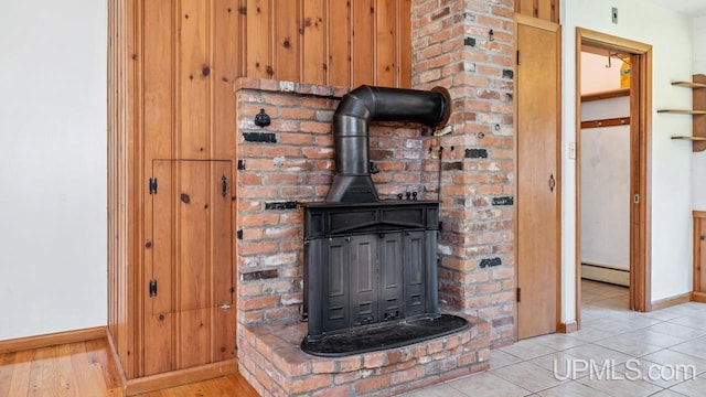 interior details featuring wooden walls, hardwood / wood-style flooring, a wood stove, and a baseboard heating unit