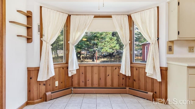 interior space featuring baseboard heating, wood walls, and light tile patterned flooring