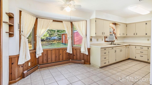 kitchen with ceiling fan, wooden walls, sink, cream cabinets, and light tile patterned floors