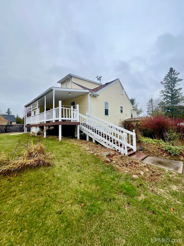 rear view of property featuring a wooden deck and a lawn