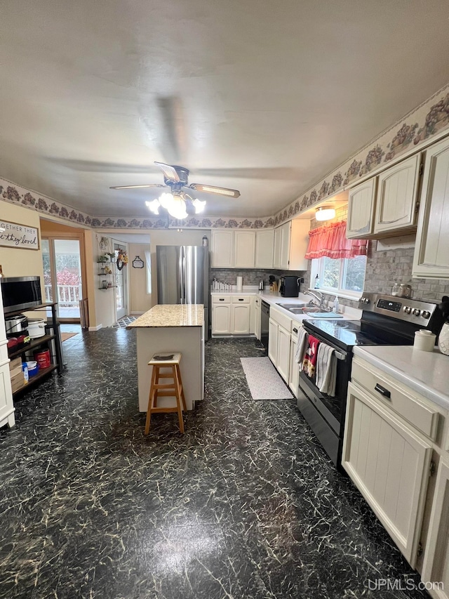 kitchen with a breakfast bar, backsplash, sink, appliances with stainless steel finishes, and a kitchen island