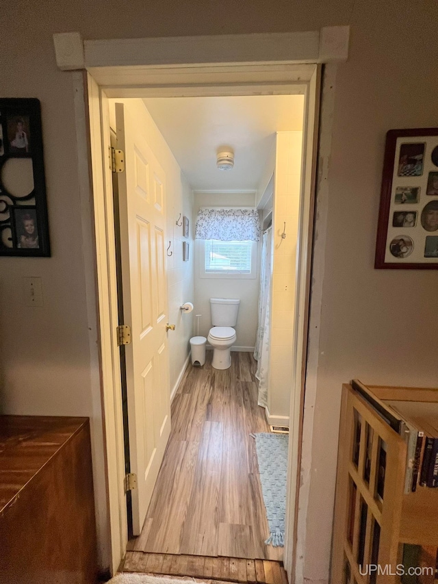 bathroom with toilet, wood-type flooring, and walk in shower