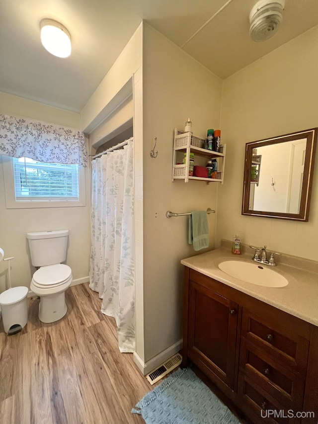 bathroom with hardwood / wood-style floors, vanity, a shower with shower curtain, and toilet