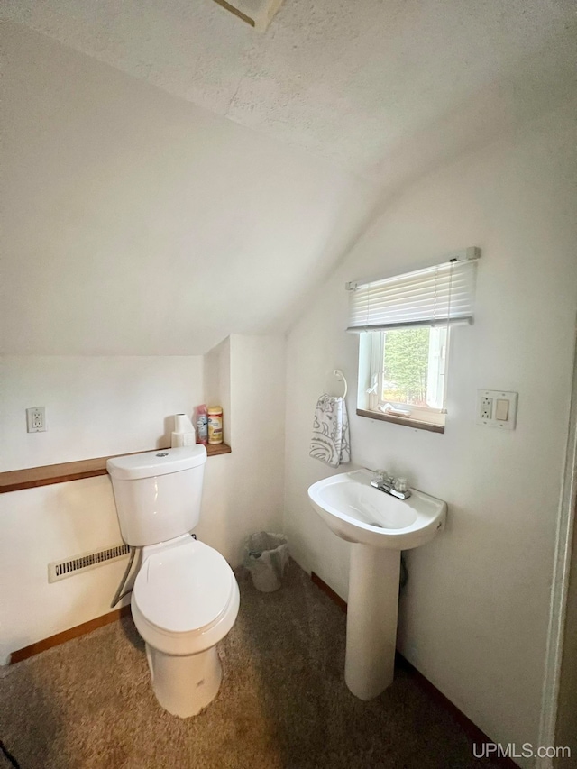 bathroom with toilet, lofted ceiling, and a textured ceiling