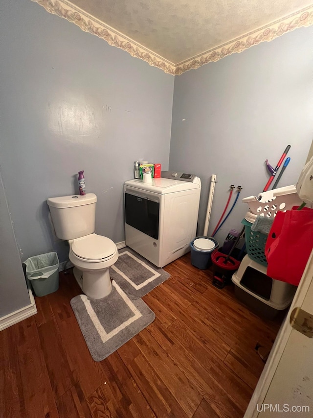 bathroom with toilet, wood-type flooring, ornamental molding, and washer / clothes dryer