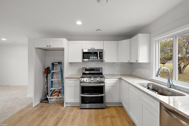 kitchen featuring white cabinets, appliances with stainless steel finishes, light wood-type flooring, and sink