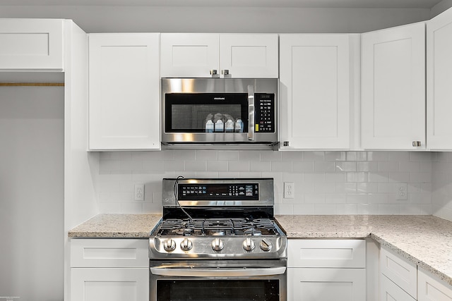 kitchen featuring decorative backsplash, light stone counters, white cabinets, and stainless steel appliances