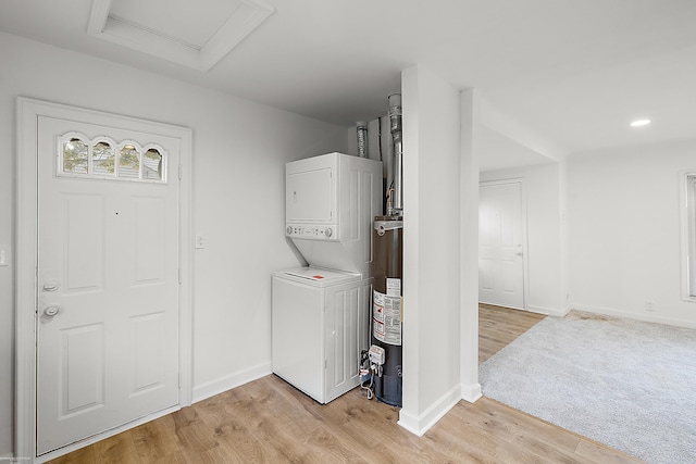 clothes washing area with stacked washer / drying machine, light wood-type flooring, and water heater