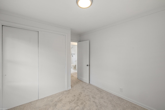 unfurnished bedroom featuring crown molding, a closet, and light colored carpet