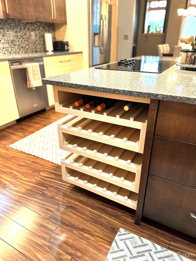 kitchen with decorative backsplash, light stone countertops, stainless steel appliances, and dark hardwood / wood-style floors