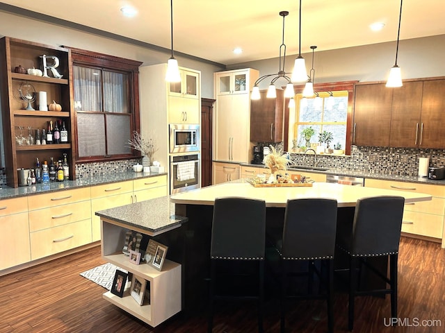 kitchen with sink, stainless steel appliances, dark hardwood / wood-style flooring, a breakfast bar area, and a kitchen island