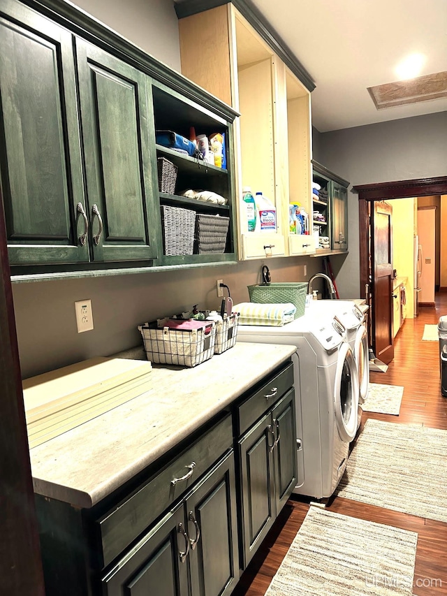 laundry area with washing machine and clothes dryer, dark wood-type flooring, and cabinets