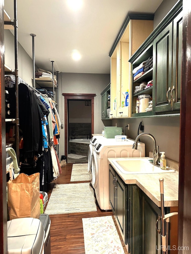 laundry room with washer and dryer, dark hardwood / wood-style floors, cabinets, and sink