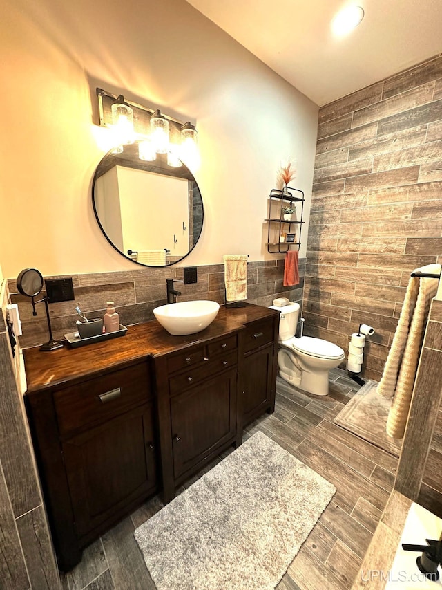 bathroom featuring tasteful backsplash, vanity, wood-type flooring, tile walls, and toilet