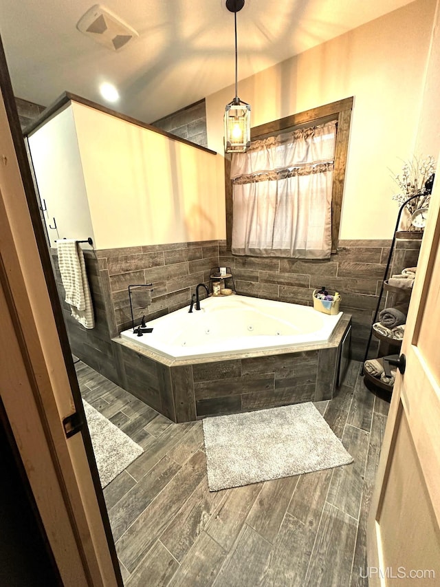 bathroom featuring a relaxing tiled tub and hardwood / wood-style flooring