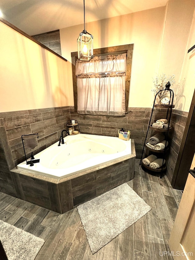 318 Iron St, Negaunee, MI 49866 - bathroom featuring a whirlpool tub, wood finished floors, and wainscoting
