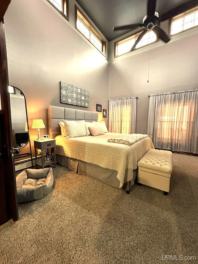 carpeted bedroom with ceiling fan and a high ceiling