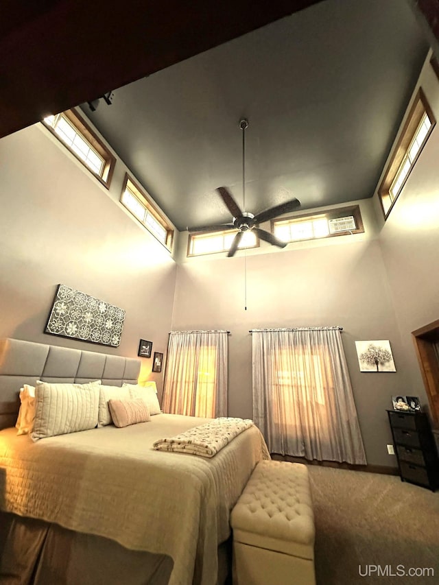 bedroom with carpet floors, ceiling fan, and a towering ceiling