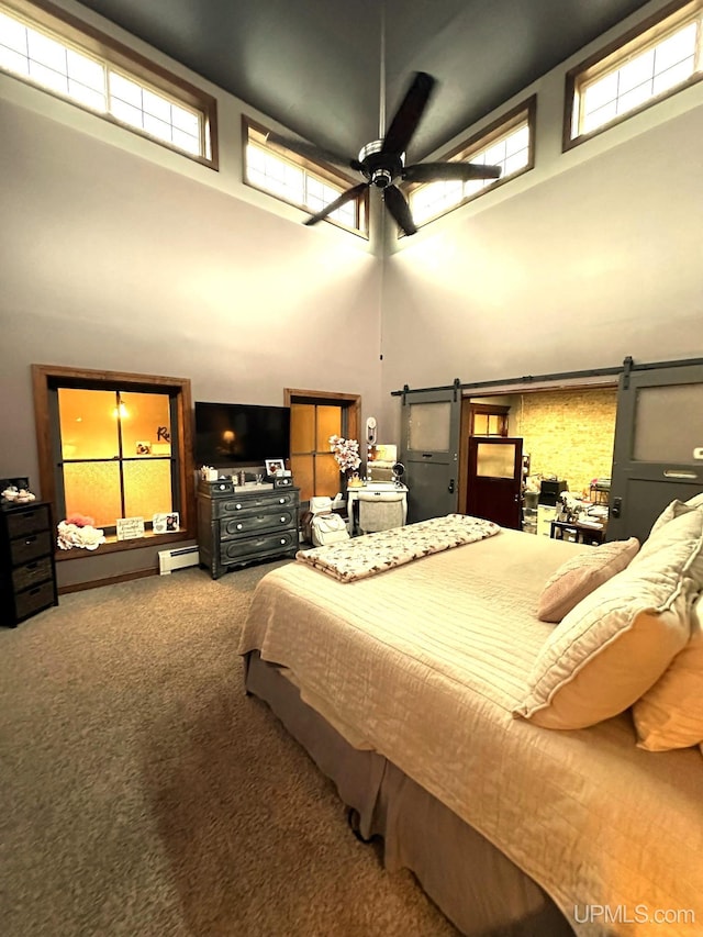 bedroom with carpet, a high ceiling, ceiling fan, a barn door, and a baseboard radiator