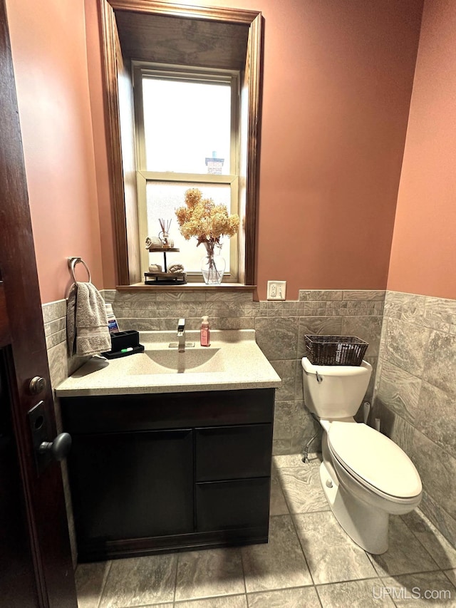 bathroom featuring vanity, toilet, and tile walls