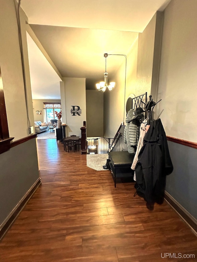 corridor with dark wood-type flooring and a notable chandelier