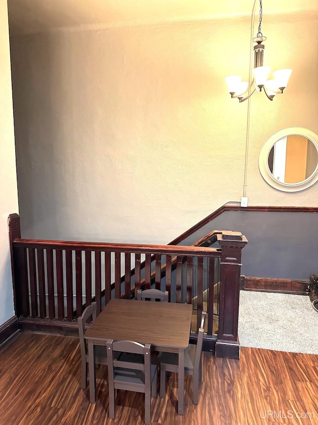 stairs featuring hardwood / wood-style floors and an inviting chandelier