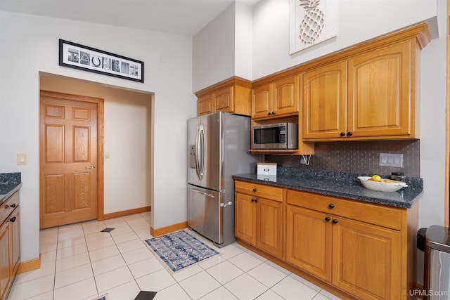 kitchen featuring tasteful backsplash, dark stone counters, vaulted ceiling, light tile patterned floors, and appliances with stainless steel finishes