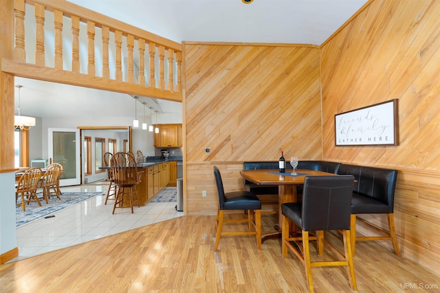 dining space with wooden walls, sink, a high ceiling, and light wood-type flooring