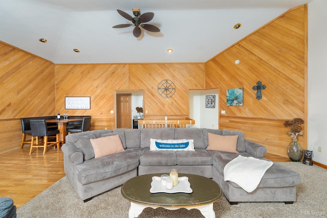 living room with hardwood / wood-style floors, ceiling fan, and wooden walls