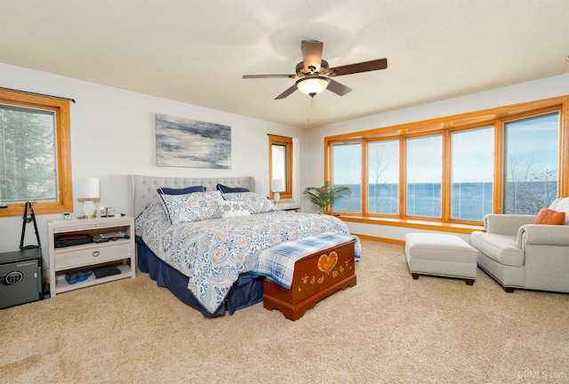 bedroom with carpet floors, a water view, and ceiling fan