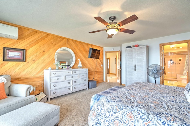 bedroom featuring ceiling fan, ensuite bathroom, wood walls, light colored carpet, and a textured ceiling