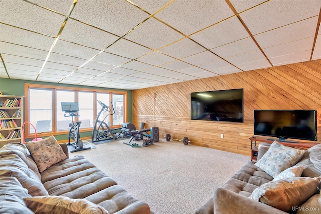 living room with carpet flooring, a drop ceiling, and wooden walls