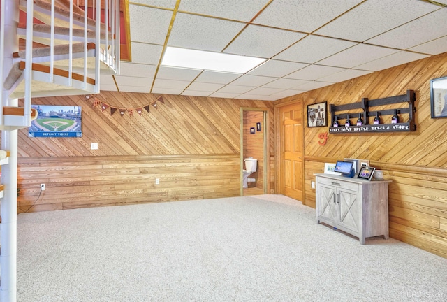 interior space featuring carpet, a paneled ceiling, and wood walls