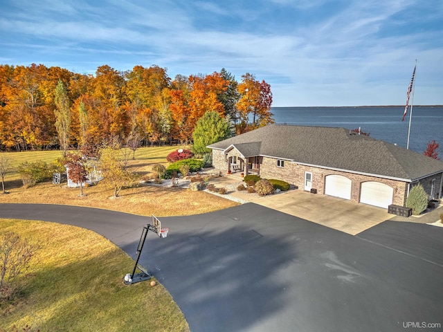 view of front facade with a front yard, a water view, and a garage