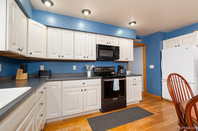 kitchen featuring white fridge, stainless steel electric range oven, and white cabinetry