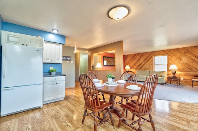 dining space featuring wooden walls and light hardwood / wood-style floors