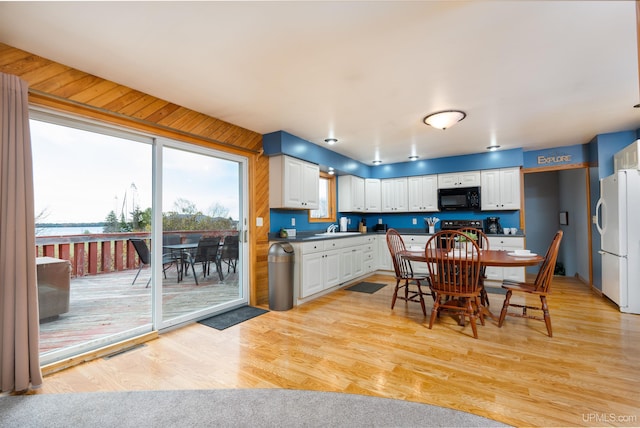 kitchen with black appliances, white cabinets, sink, and light hardwood / wood-style flooring