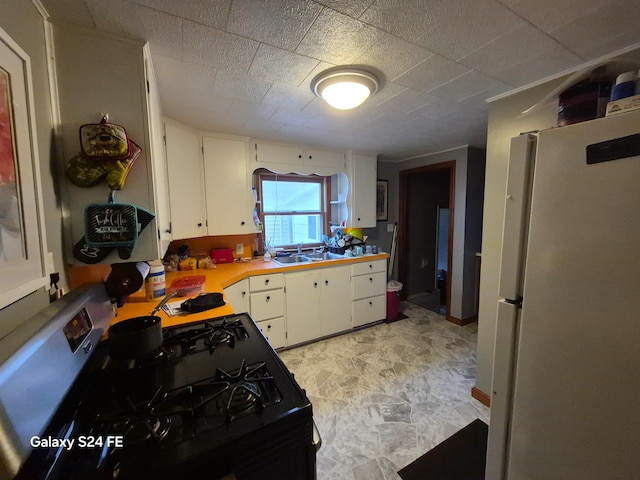 kitchen featuring black electric range, white refrigerator, white cabinetry, and sink