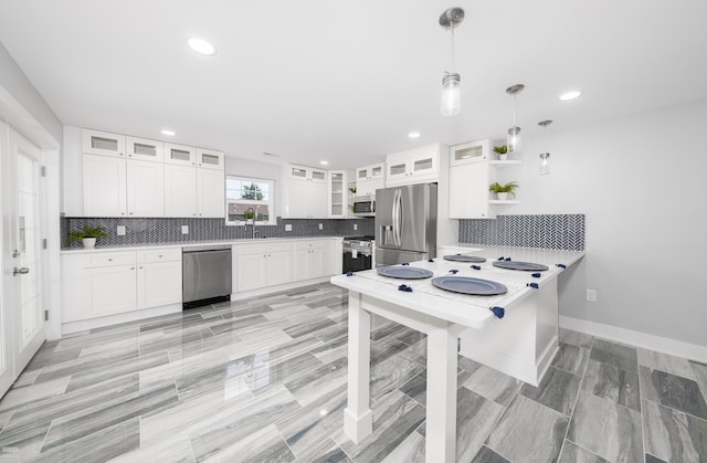 kitchen with backsplash, kitchen peninsula, appliances with stainless steel finishes, decorative light fixtures, and white cabinetry