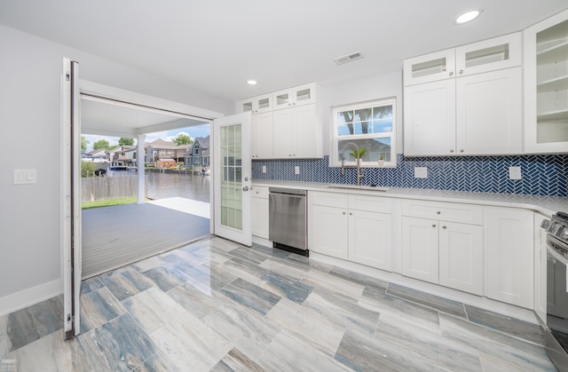 kitchen with a water view, backsplash, white cabinets, and appliances with stainless steel finishes